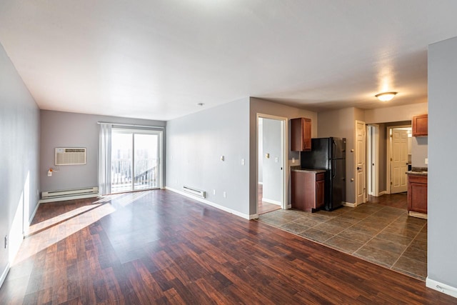 unfurnished living room with a baseboard heating unit, a wall mounted air conditioner, and dark wood-type flooring