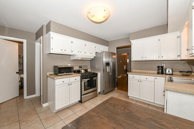 kitchen featuring light tile patterned flooring, appliances with stainless steel finishes, sink, and white cabinets