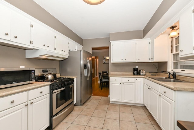 kitchen with sink, stainless steel appliances, white cabinets, and light tile patterned flooring