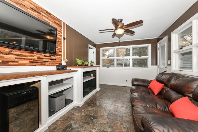 living room featuring crown molding, wooden walls, and ceiling fan