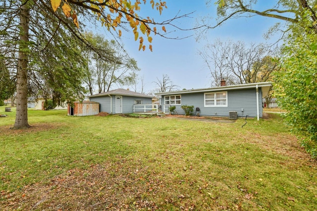 rear view of property with central air condition unit, a shed, and a lawn