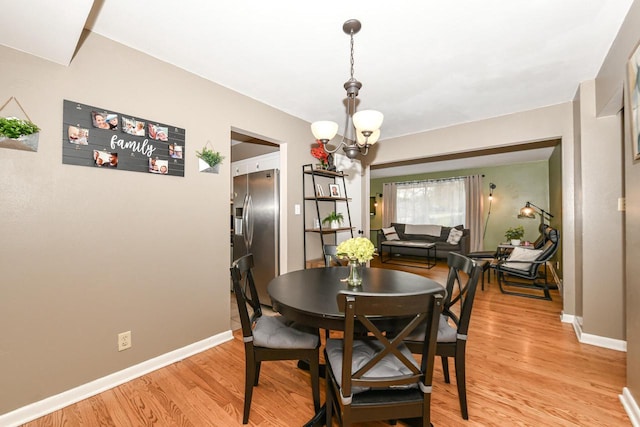 dining area with an inviting chandelier and light hardwood / wood-style flooring