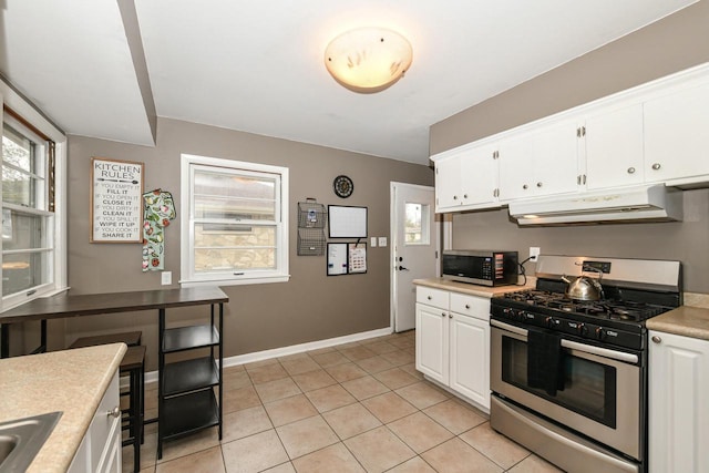 kitchen with light tile patterned flooring, appliances with stainless steel finishes, sink, and white cabinets