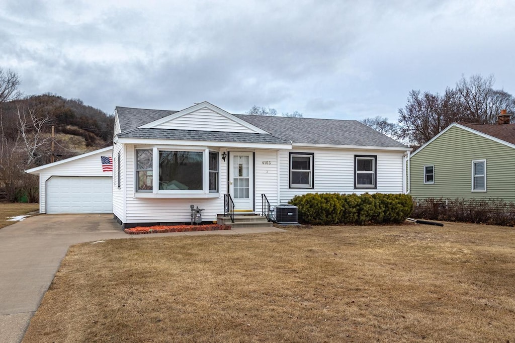 view of front of property featuring an outbuilding, a garage, central AC unit, and a front lawn