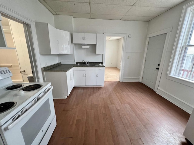 kitchen featuring wood-type flooring, a paneled ceiling, white cabinets, and white range with electric cooktop