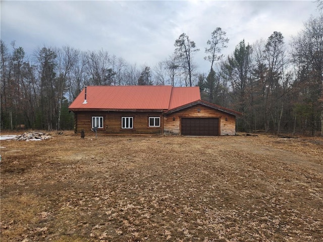 view of front of property with a garage, metal roof, and driveway