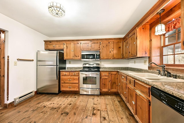 kitchen with pendant lighting, sink, appliances with stainless steel finishes, wood-type flooring, and a baseboard radiator