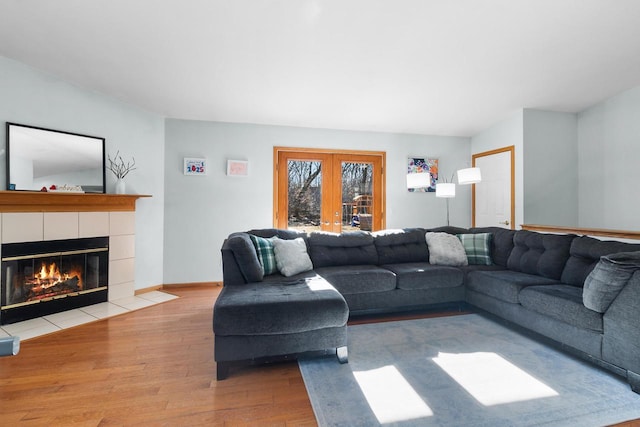 living room featuring light hardwood / wood-style flooring, a tile fireplace, and french doors