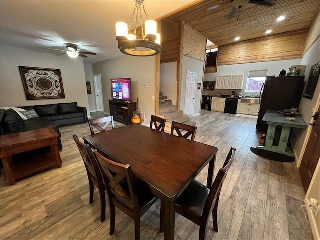 dining space featuring lofted ceiling, light hardwood / wood-style floors, ceiling fan with notable chandelier, and wooden ceiling