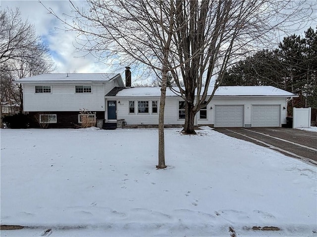 snow covered rear of property featuring a garage