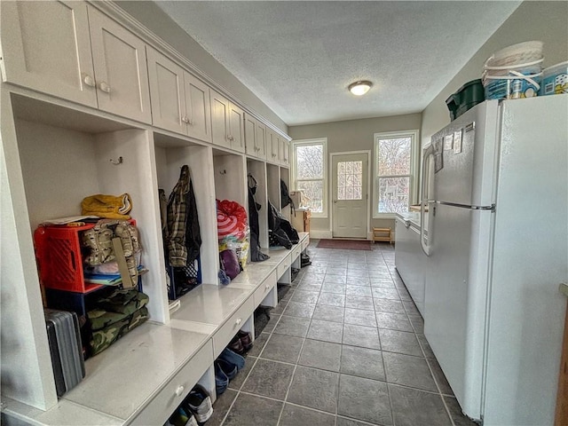 mudroom featuring a textured ceiling and dark tile patterned floors