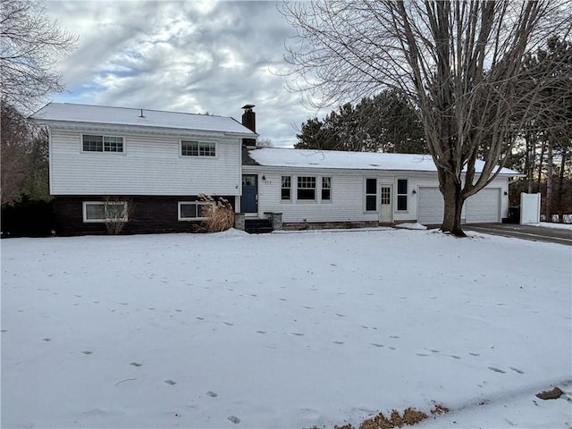 snow covered rear of property featuring a garage