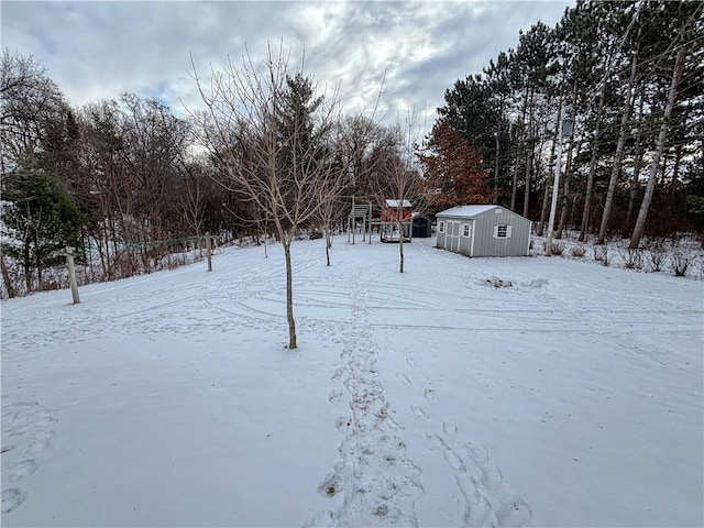 snowy yard featuring a storage unit