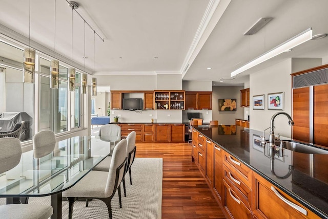 kitchen featuring sink, paneled built in refrigerator, dark hardwood / wood-style floors, ornamental molding, and decorative light fixtures