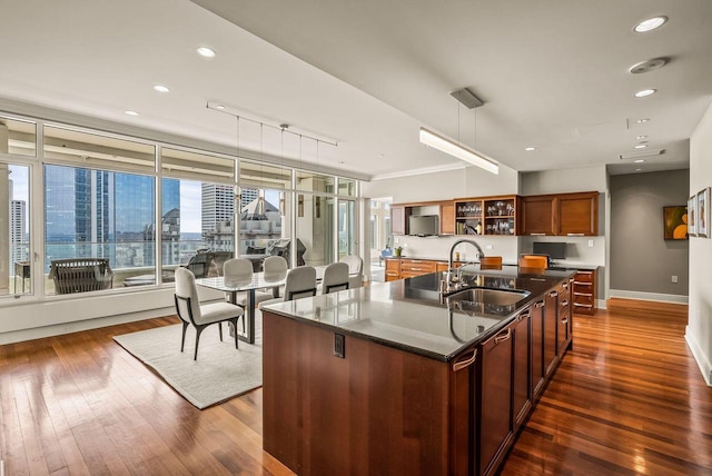 kitchen with hanging light fixtures, sink, a center island with sink, and dark hardwood / wood-style flooring