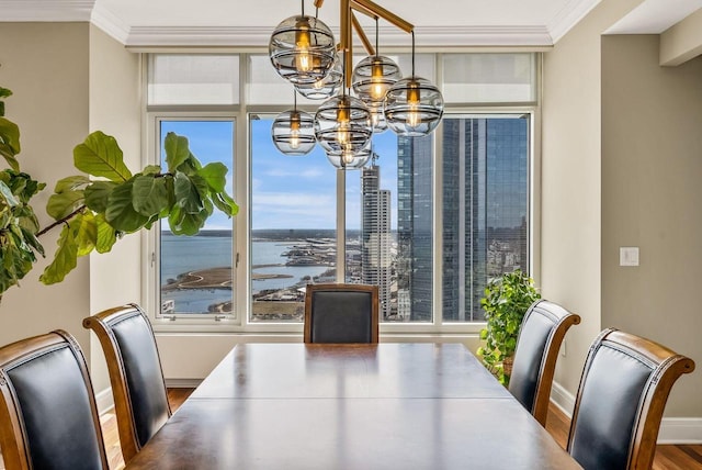 dining space featuring a water view, ornamental molding, an inviting chandelier, and wood-type flooring