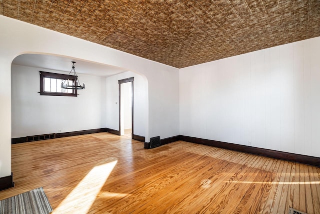 unfurnished room with an inviting chandelier, hardwood / wood-style floors, and brick ceiling