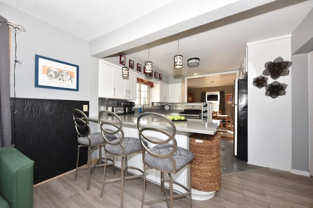 kitchen with pendant lighting, stainless steel appliances, dark hardwood / wood-style floors, white cabinets, and kitchen peninsula