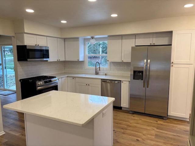 kitchen featuring white cabinetry, stainless steel appliances, decorative backsplash, and light hardwood / wood-style flooring