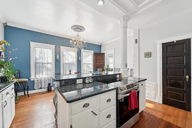 kitchen with pendant lighting, stainless steel electric range oven, white cabinets, a kitchen island, and ornate columns