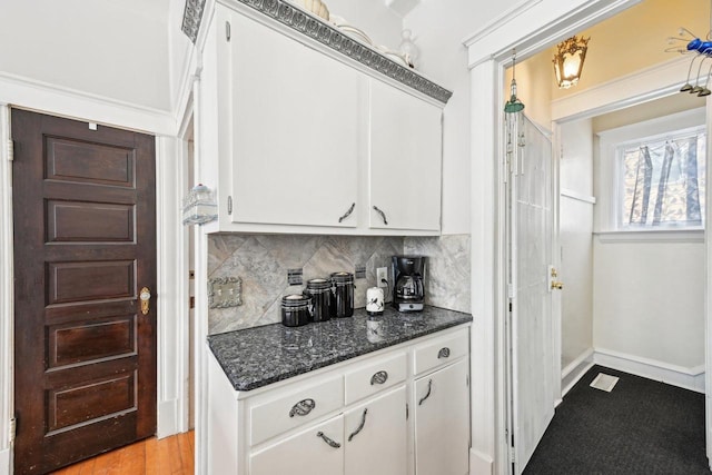 kitchen featuring white cabinetry, decorative backsplash, light hardwood / wood-style floors, and dark stone countertops