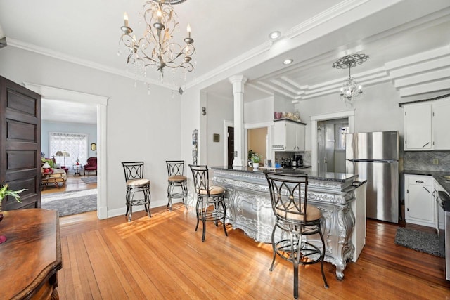 kitchen featuring tasteful backsplash, white cabinetry, appliances with stainless steel finishes, and a kitchen bar