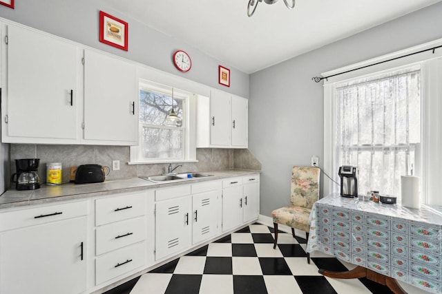 kitchen featuring tasteful backsplash, white cabinetry, and sink