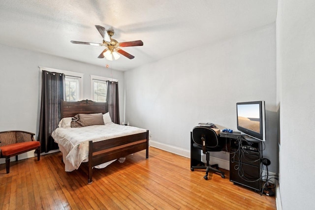 bedroom with ceiling fan, light hardwood / wood-style floors, and a textured ceiling