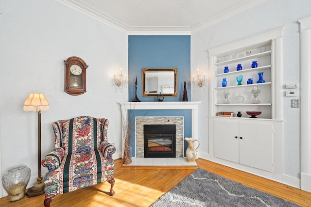 sitting room with hardwood / wood-style floors, a stone fireplace, and ornamental molding