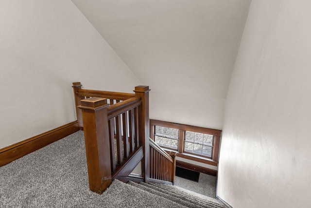 stairway featuring lofted ceiling and carpet floors