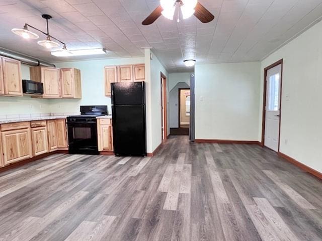 kitchen with light brown cabinets, hardwood / wood-style floors, hanging light fixtures, and black appliances