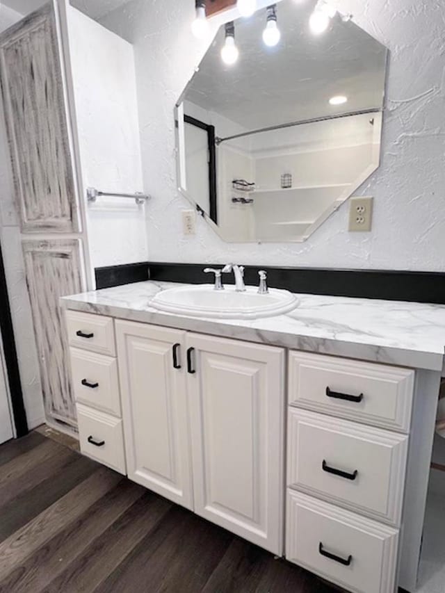 bathroom featuring wood finished floors, vanity, and a textured wall