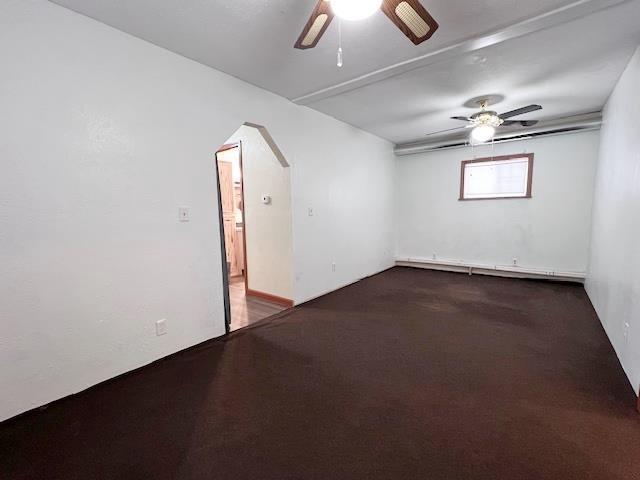 unfurnished room featuring a baseboard radiator, arched walkways, carpet floors, and ceiling fan