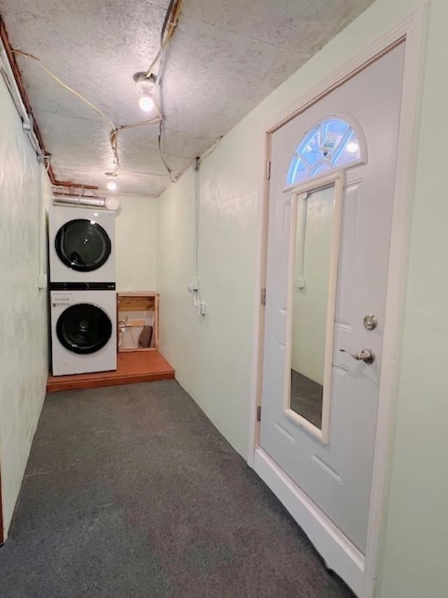 laundry room with carpet flooring, stacked washer and clothes dryer, laundry area, and a textured ceiling