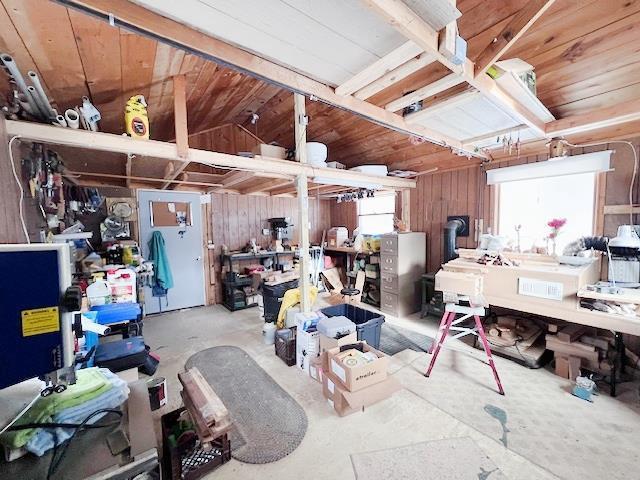 miscellaneous room featuring lofted ceiling, wood walls, and a workshop area