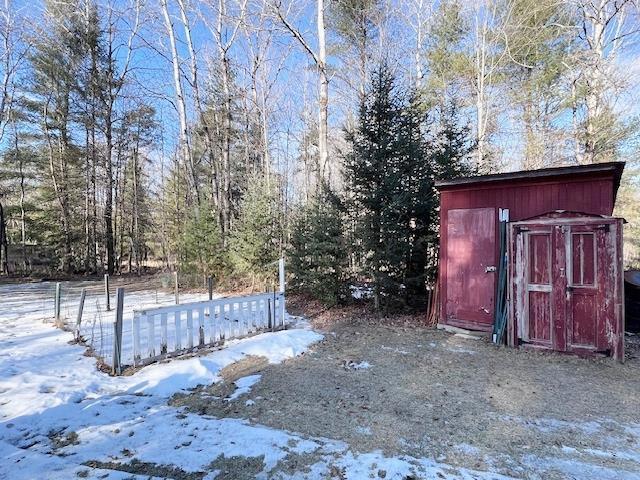 snowy yard with an outdoor structure and a shed