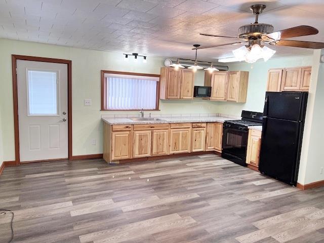 kitchen with black appliances, light wood-style flooring, light brown cabinets, and light countertops