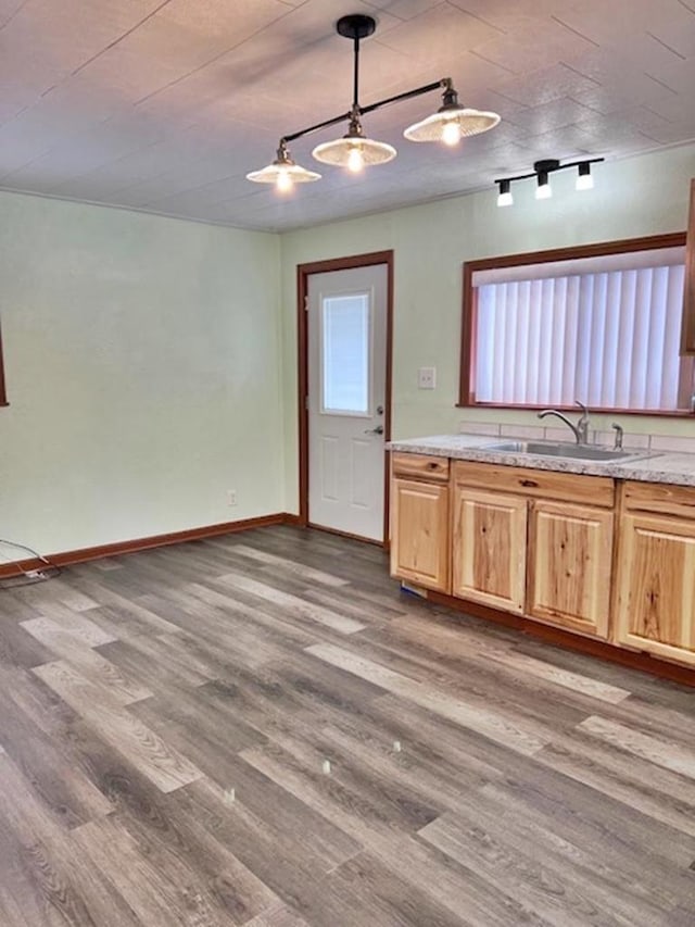 kitchen featuring a sink, light wood-type flooring, baseboards, and pendant lighting