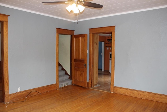 spare room featuring wood-type flooring, ceiling fan, and crown molding