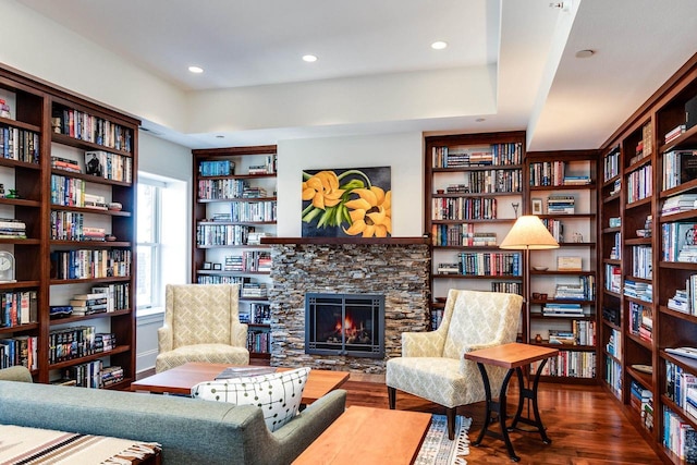 sitting room featuring a stone fireplace and dark hardwood / wood-style flooring