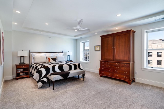 carpeted bedroom with ceiling fan and a raised ceiling