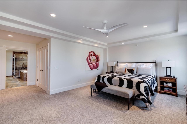 bedroom featuring light carpet, connected bathroom, a raised ceiling, and ceiling fan