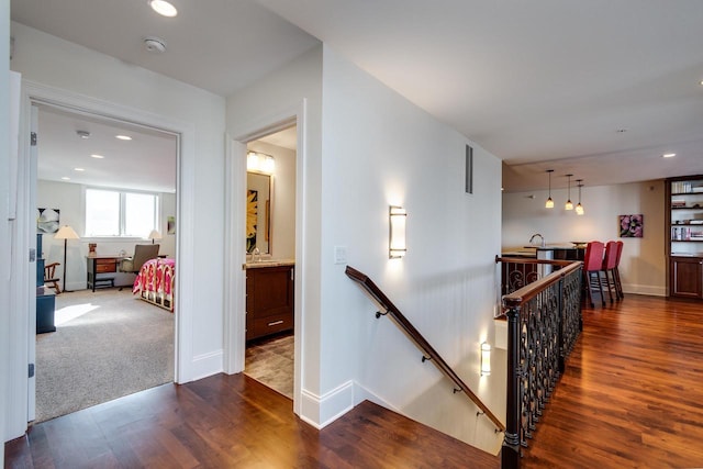 corridor with dark colored carpet and sink