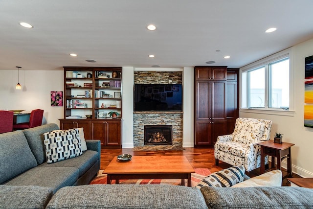 living room featuring a stone fireplace and dark wood-type flooring