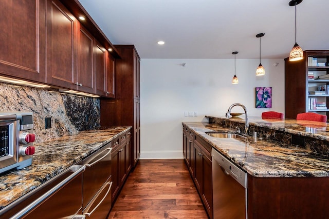 kitchen featuring sink, hanging light fixtures, tasteful backsplash, stainless steel dishwasher, and dark stone counters