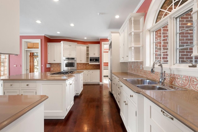 kitchen with white cabinetry, sink, decorative backsplash, a center island, and stainless steel appliances