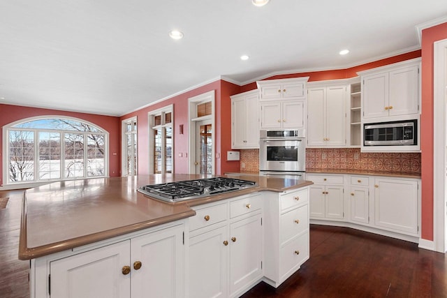 kitchen with tasteful backsplash, appliances with stainless steel finishes, dark hardwood / wood-style flooring, a kitchen island, and white cabinets