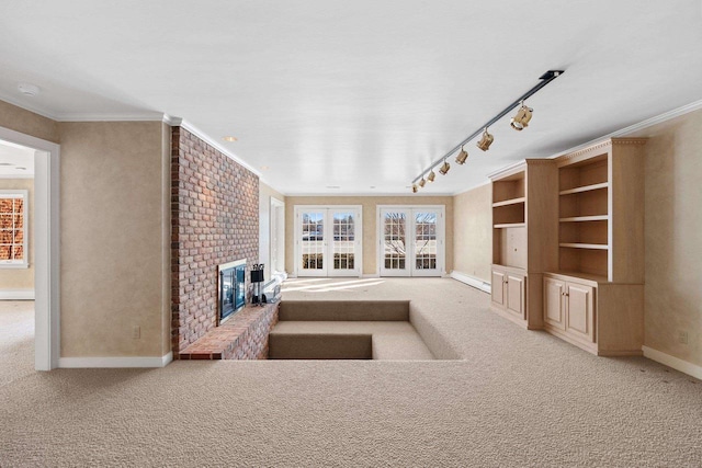 unfurnished living room featuring light colored carpet, ornamental molding, a fireplace, and rail lighting