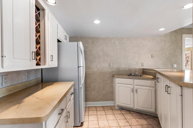 kitchen featuring refrigerator, sink, white cabinets, and light tile patterned flooring