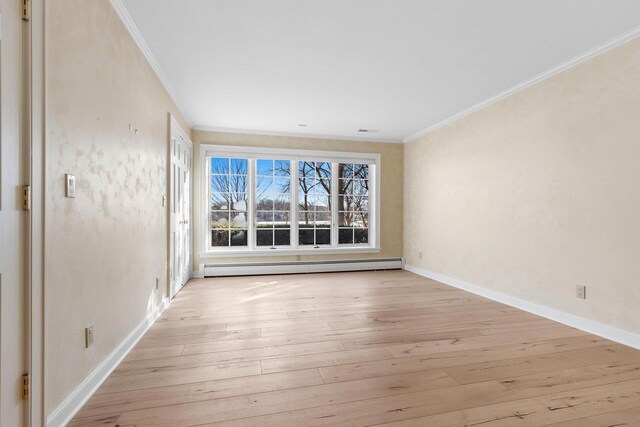 empty room with crown molding, a baseboard heating unit, and light wood-type flooring